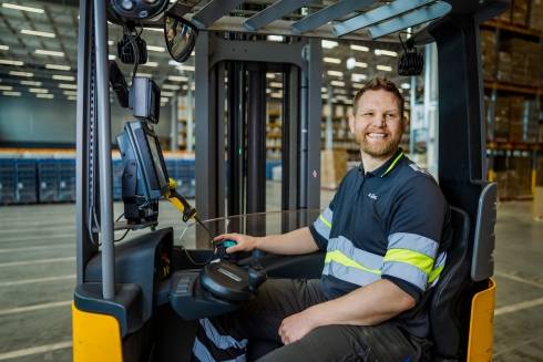 Varastotyöntekijä ajaa trukilla ja nauraa
